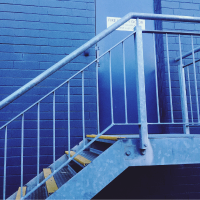 Commercial property risk - close-up of emergency exit and stairs against blue wall